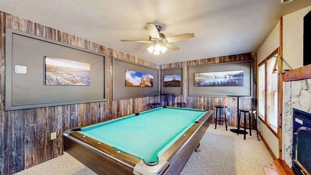 A pool table with a ceiling fan, wooden panel walls, and framed pictures. - Hilltop Getaway - Hilltop Home • Hot Tub & Billiards (Lead)