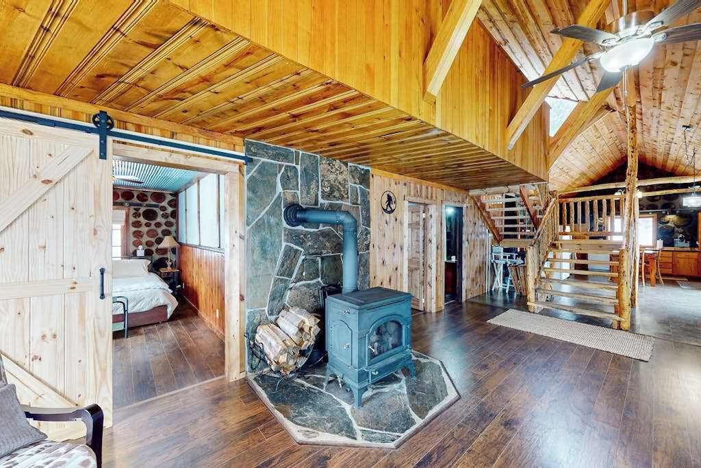 Un intérieur rustique avec une cheminée en pierre, des poutres en bois et un escalier.