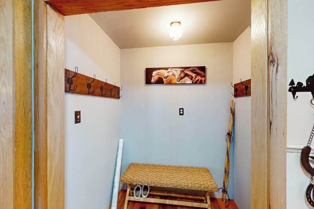 A room with a wooden bench, wall-mounted hooks, and a framed picture.