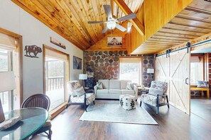A spacious living room with a high ceiling, a stone wall, and a sliding barn door.