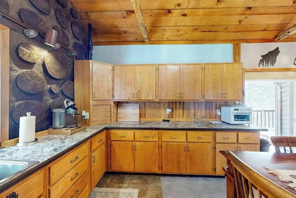 A kitchen with wooden cabinets, granite countertops, and a microwave.