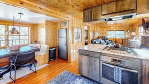 Ein Holzblockhaus-Interieur mit Küche, Essbereich und Wohnraum.