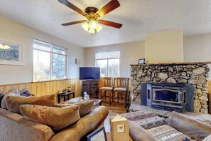 Ein Wohnzimmer mit Kamin aus Stein, einem Fernseher und einem Deckenventilator.