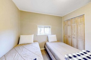 Ein Zimmer mit zwei Betten, einem Fenster und einem Holzschrank.