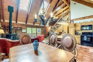 A wooden interior with a dining table, chairs, a chandelier, and a kitchen area. - Pikes Peak Retreat - Cabin w/ Pikes Peak & Forest Access (Divide)