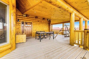 A log cabin with a wooden deck, a dining table with chairs, and a staircase leading to the upper level. - Liberty Lodge at Terry Peak - Ski-In/Ski-Out Lodge • Hot Tub (Lead)