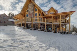 A log cabin with a stone chimney, a balcony, and a snow-covered ground. - Liberty Lodge at Terry Peak - Ski-In/Ski-Out Lodge • Hot Tub (Lead)