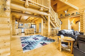 A log cabin interior with a staircase, a kitchen, a living area with a couch and coffee table, and a patterned rug. - Liberty Lodge at Terry Peak - Ski-In/Ski-Out Lodge • Hot Tub (Lead)