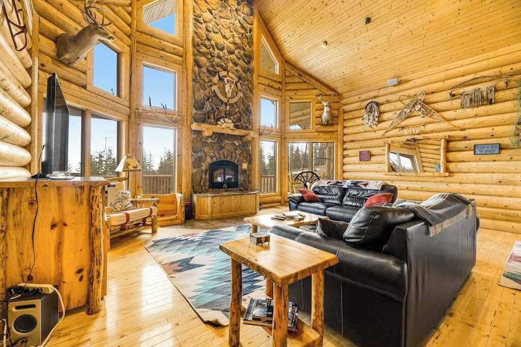 L’intérieur d’une cabane en rondins, avec une cheminée, un canapé en cuir et des murs en bois.