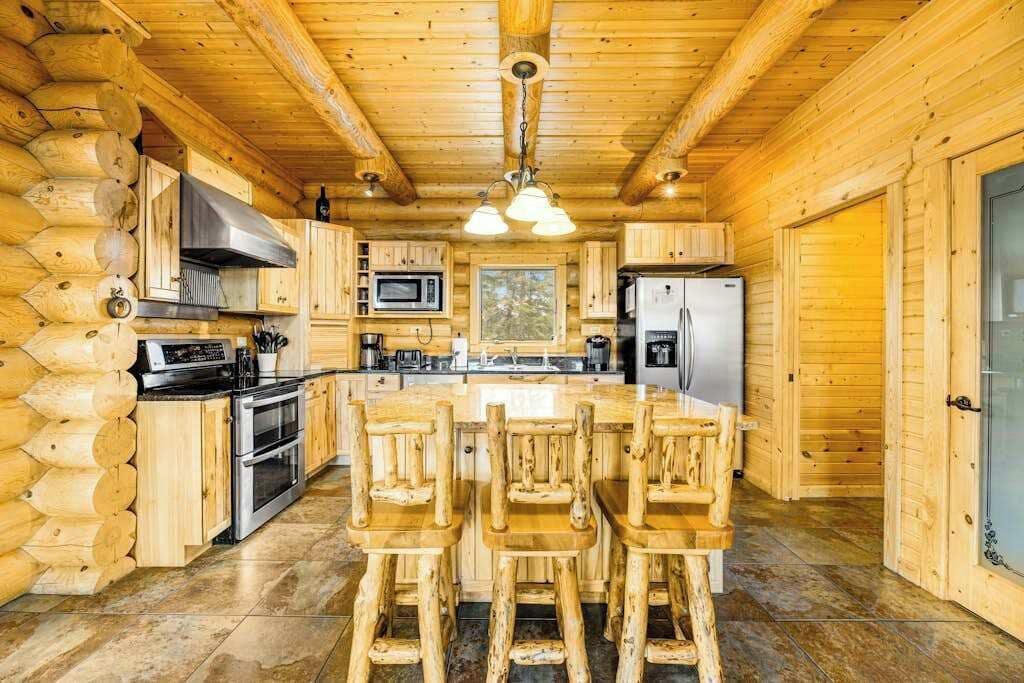 Ein Holzblockhaus-Interieur mit Küche, Essbereich und einem großen Fenster.