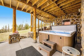 A wooden cabin with a stone wall, a hot tub, and a covered patio. - Liberty Lodge at Terry Peak - Ski-In/Ski-Out Lodge • Hot Tub (Lead)