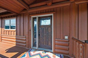 A wooden cabin with a sliding glass door and a window. - Reunion Lodge • Hot Tub, Game Room & Views (Sturgis)
