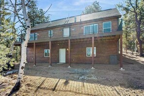 Eine zweistöckige Holzhütte mit einem Balkon, umgeben von Bäumen.
