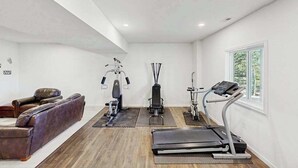 Uma academia em casa com equipamentos de exercícios, um banco e uma cadeira de massagem.