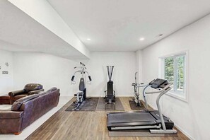 Ein Heimfitnessraum mit Trainingsgeräten, einer Bank und einem Massagesessel.