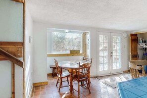 A dining area with a wooden table and chairs, a window with a view of trees, and a door leading outside. - Friends & Family Base Camp - Dog-Friendly 3-Story Group Getaway (Woodland Park)