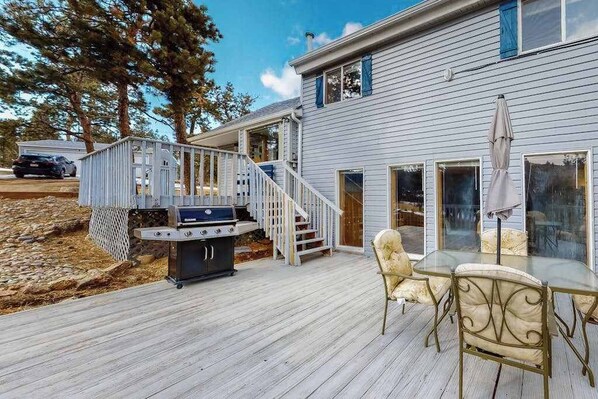 A house with a deck, outdoor grill, and a dining area with chairs and a table. - Friends & Family Base Camp - Dog-Friendly 3-Story Group Getaway (Woodland Park)