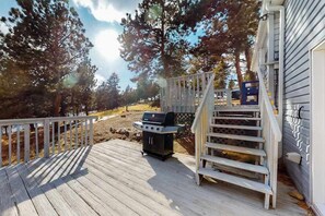 A wooden deck with a grill, a white staircase, and a view of trees. - Friends & Family Base Camp - Dog-Friendly 3-Story Group Getaway (Woodland Park)