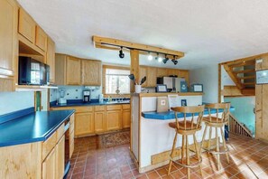 Eine Küche mit Holzschränken, einer blauen Arbeitsplatte, einer Kaffeemaschine und einer Bar mit Hockern.