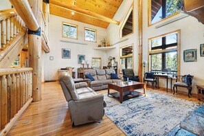 A spacious living room with a large sectional sofa, a coffee table, and a fireplace. There are multiple windows providing natural light and views of the outdoors. - Boulder Ridge Lodge - Hot Tub Log Cabin Near Golf Course (Lead)