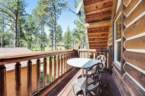 A wooden deck with a table and chairs, overlooking a forested area. - Log Lodge • Hot Tub • Game Room • Near Terry Peak (Lead)