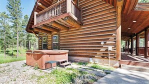 Eine Blockhütte mit Whirlpool und Sitzgelegenheit im Freien.