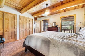 A bedroom with a large bed, wooden wardrobe, and a dresser. - Log Lodge • Hot Tub • Game Room • Near Terry Peak (Lead)