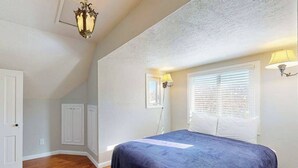 Un dormitorio con cama, una ventana con persianas, una puerta y una lámpara de techo.