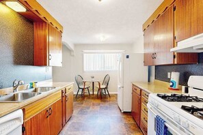 Una cocina compacta con armarios de madera, una estufa a gas y un refrigerador.