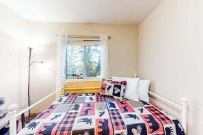 Ein Schlafzimmer mit einem Bett, einem Fenster mit Vorhängen und einem Nachttisch.