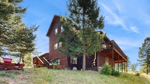 Eine mehrstöckige Holzhütte mit Balkon, umgeben von Bäumen.