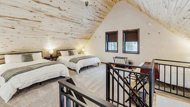 A bedroom with two beds, a ceiling fan, and a view of the outdoors through two windows. - Sundby Cabin - New Chalet • Walk to Skiing (Lead)