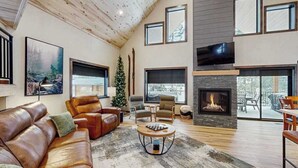 A modern living room with a fireplace, leather sofas, and a large TV. - Sundby Cabin - New Chalet • Walk to Skiing (Lead)
