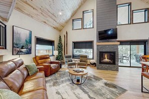 Ein modernes Wohnzimmer mit Kamin, Ledersofas und einem großen Fernseher.