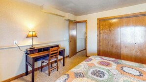 A bedroom with a bed, a desk, a chair, a lamp, and a wardrobe. - Secluded Mountain Escape • Full Kitchen (Cripple Creek)