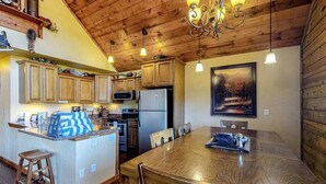 A kitchen with wooden cabinets, a central island, and a dining table. - Secluded Mountain Escape • Full Kitchen (Cripple Creek)