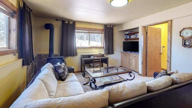A cozy living room with a sofa, a coffee table, a TV, and a bookshelf. - Secluded Mountain Escape • Full Kitchen (Cripple Creek)