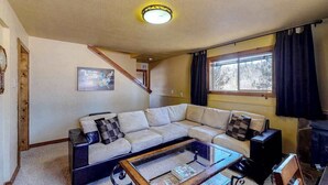 A living room with a sectional sofa, a coffee table, a fireplace, and a window with curtains. - Secluded Mountain Escape • Full Kitchen (Cripple Creek)