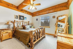 A bedroom with a wooden bed frame, a ceiling fan, a window, and a mirror. - Tetro Rock Retreat - Game Room & Forest Views (Deadwood)