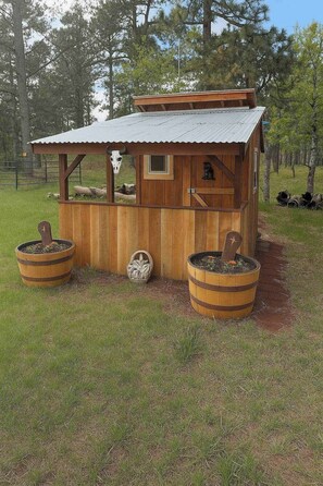 A rustic wooden structure with a metal roof, two barrels, and a wheel. - Tetro Rock Retreat - Game Room & Forest Views (Deadwood)