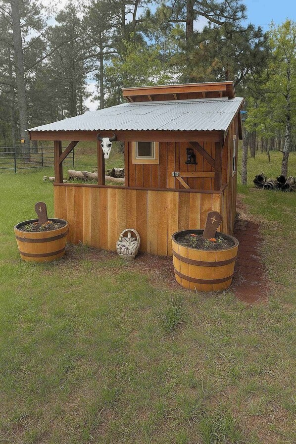 A rustic wooden structure with a metal roof, two barrels, and a wheel. - Tetro Rock Retreat - Game Room & Forest Views (Deadwood)