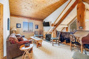 Ein gemütliches Wohnzimmer im Loft-Stil mit schrägen Wänden, einem Kamin, einer Couch, einem Tisch und einem Fernseher.