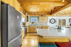Eine Küche mit Holzausstattung, einem Edelstahlkühlschrank und einer großen Kochinsel mit Sitzgelegenheiten.