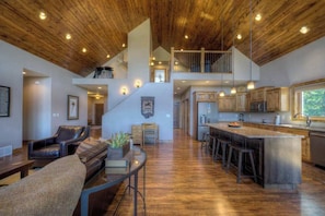 A spacious living area with a high ceiling, wooden flooring, and a central seating arrangement. - Vacation Court Lodge - Mountain-View Lodge • Private Hot Tub (Sturgis)