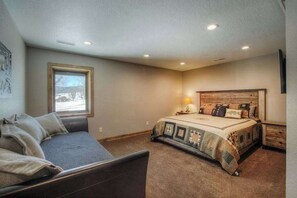 Ein Schlafzimmer mit einem Bett, einem Sofa, einem Fenster und einem Nachttisch.