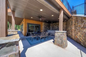 An outdoor patio area with a stone wall, a wooden deck, and a seating arrangement. - Vacation Court Lodge - Mountain-View Lodge • Private Hot Tub (Sturgis)