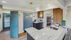 A modern kitchen with a marble countertop, wooden cabinets, and pendant lighting. - Mtn-View Apt • Private Hot Tub, Dogs OK (Green Mountain Falls)