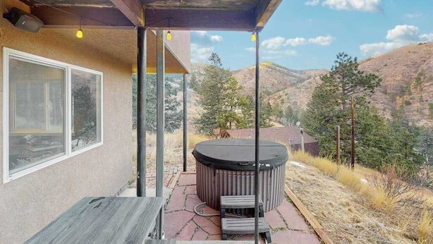A patio with a hot tub, outdoor seating, and a view of a mountainous landscape. - Mtn-View Apt • Private Hot Tub, Dogs OK (Green Mountain Falls)