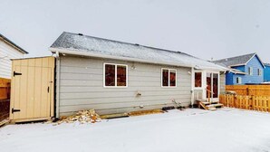 Ett envåningshus med ett garage, en inglasad veranda och ett trästaket.