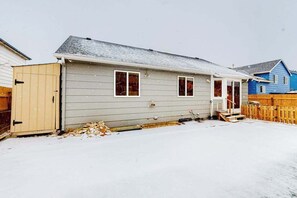 Ein eingeschossiges Haus mit Garage, einer überdachten Veranda und einem Holzzaun.